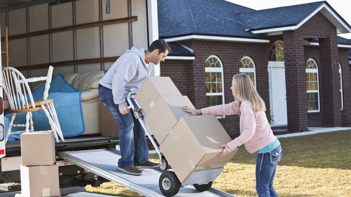 Couple unloading boxes from moving van