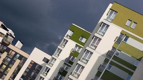 Photo of apartments towers taken at 45-degree angle, with stormy skies above.