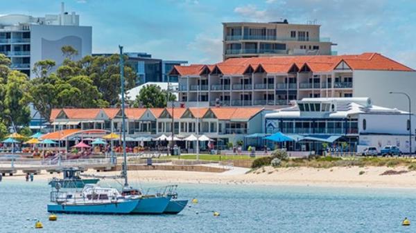 A catamaran moored on Rockingham foreshore with apartment and retail buildings in background.