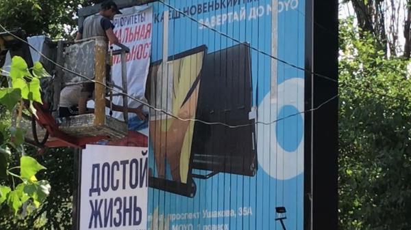 Pro-Russian propaganda being put up on a big billboard. once it's up, it will read "with Russia, a decent life" and is directed at pensioners