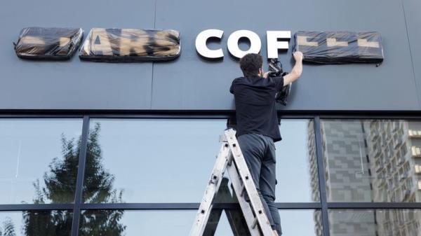 A staff removes cover from a sign of the new coffee shop "Stars Coffee", which opens following Starbucks Corp company's exit from the Russian market, in Moscow, Russia August 18, 2022. REUTERS/Maxim Shemetov
