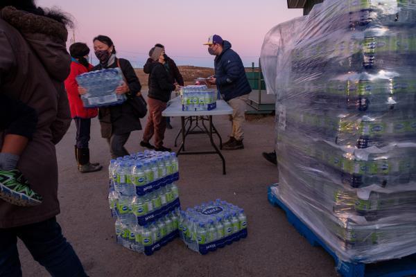 Residents line up to collect bottled water after fuel contamination was confirmed in city supply