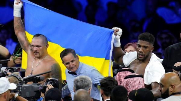 Ukraine's Oleksandr Usyk, left, celebrates after beating Britain's Anthony Joshua, as they both hold a Ukrainian flag after their world heavyweight title fight at King Abdullah Sports City in Jeddah, Saudi Arabia, Sunday, Aug. 21, 2022. (AP Photo/Hassan Ammar)