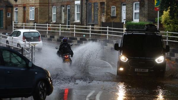 Vehicles drive through a flooded street of a residential area after heavy rain hits London, Britain August 25, 2022. REUTERS/Hannah Mckay
