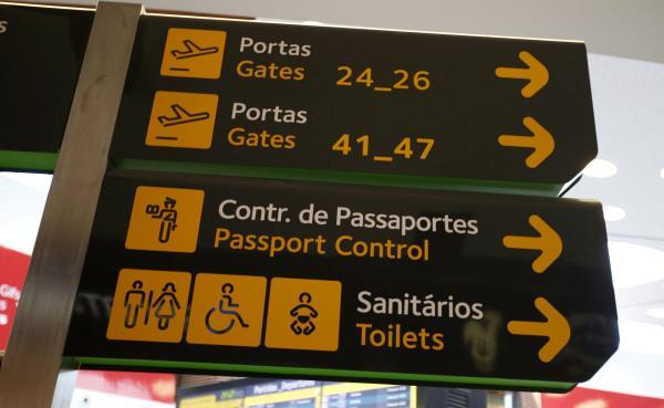 Gates, passport control and toilets signs are seen at Lisbon's airport