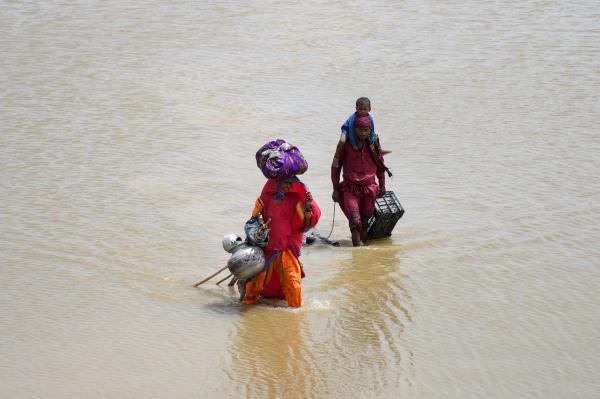 A family with their belongings wade through rain waters following rains and floods during the monsoon season in Jamshoro