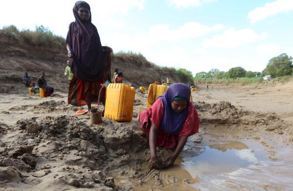 People collect water from shallow wells dug along the Shabelle River bed, which is dry due to drought in Somalia's Shabelle region
