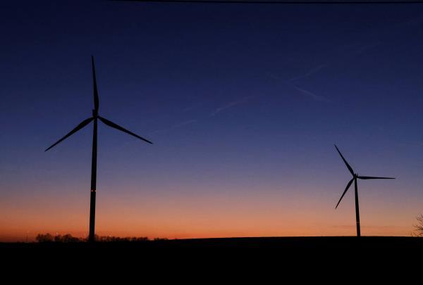 Sun sets behind power-generating windmill turbines near Waremme