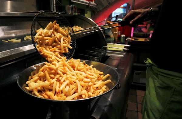 A cook prepares fries in a cafe at the Frietmuseum in Bruges