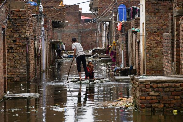 A man and a girl use a makeshift raft as they cross a flooded street, following rains during the monsoon season in Hyderabad