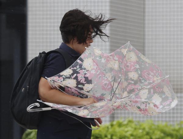 A woman makes her way in strong winds brought by Typhoon Hinnamnor in Naha