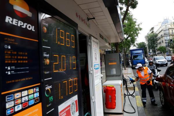 A worker prepares to pump gas into a car at a Repsol gas station in Madrid