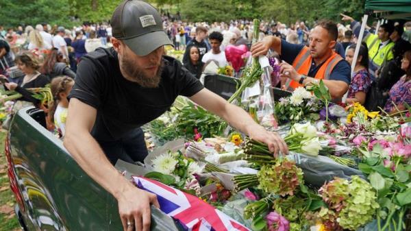 Staff from the Royal household distribute flowers to the public in Green Park, near Buckingham Palace, London. Queen Elizabeth II's coffin is travelling from Balmoral to Edinburgh, where it will lie at rest at the Palace of Holyroodhouse. Picture date: Sunday September 11, 2022.

