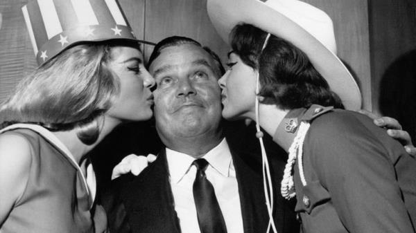 PA NEWS PHOTO 6/11/62 BILLY BUTLIN KING OF THE HOLIDAY CAMP "BUTLINS" RECEIVING A DUAL KISS FROM MISS AMERICA AND MISS CANADA AS THEY COMPETE FOR THE MISS WORLD TITLE.  *  11/4/01: The great British holiday resort Butlins celebrates its 65th birthday. Butlins, that has launched the careers of celebrities past and present, first opened its doors to holidaymakers in 1936 in Skegness, Lincolnshire. Their famous Redcoats have kept the work-weary entertained at resorts across the country. 