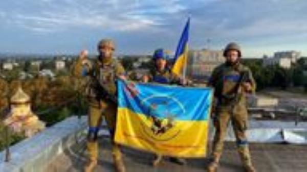 Ukrainian soldiers hold a flag at a rooftop in Kupiansk, Ukraine in this picture obtained from social media released on September 10, 2022. Telegram @kuptg/via REUTERS THIS IMAGE HAS BEEN SUPPLIED BY A THIRD PARTY. MANDATORY CREDIT. NO RESALES. NO ARCHIVES.