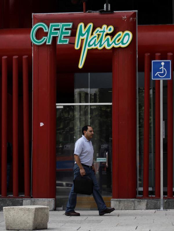 A man walks past the logo of Mexico's state-run electricity utility known as the Federal Electricity Commission, or CFE by its Spanish acronym, outside its Mexico City headquarters