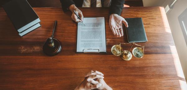 An overhead picture of two people sitting across the other at a desk, with only hands visible going over a document.