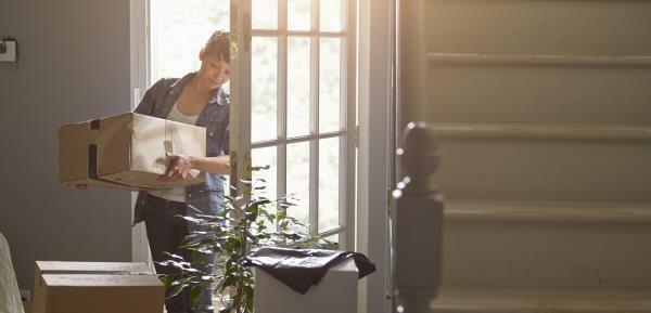 woman carrying a packing box into her new home