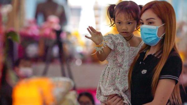 Paweenuch Supolwon, held by her mother Anonpai Srithong, 35, waves goodbye to her deceased friends' coffins inside a temple in Thailand. Pic: AP