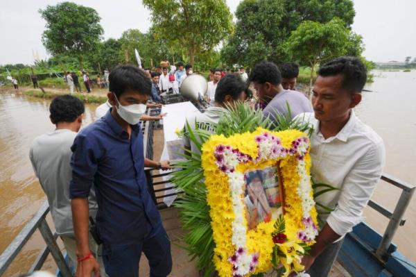 A portrait of boat accident victim Chanda July is carried by her relative during a funeral procession in Cambodia on October 14, 2022 