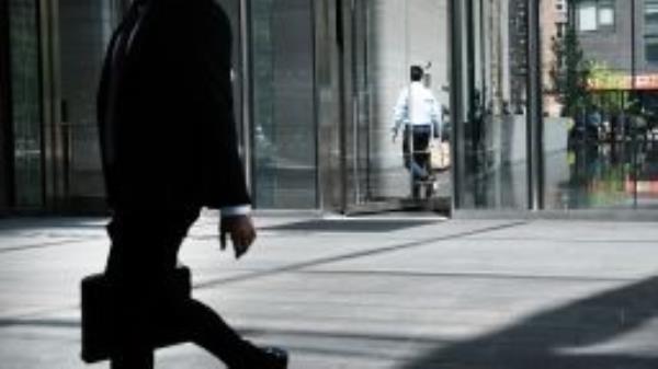People walk on a street past a business on May 12, 2022 in New York City. 