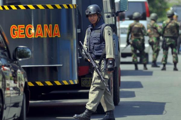 An officer of Indonesia's elite counter terrorism unit stands on the road, near a unit truck, outside a house in Solo following a raid