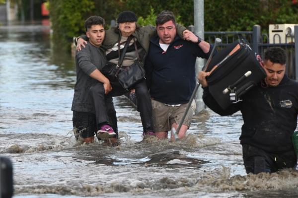 Two men carry a woman through floodwater in the Melbourne suburb of Maribyrnong, Australia.