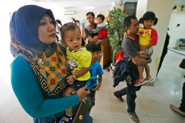 Indonesian parents bring their children to a hospital in 2016 