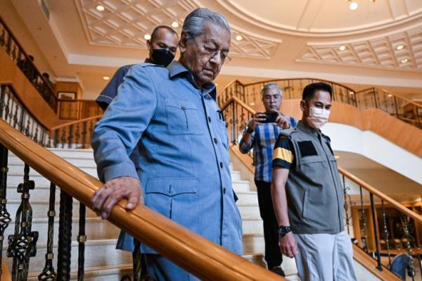 Mahathir Mohamad in blue suit walks down the staircase at his foundation in Putrajaya
