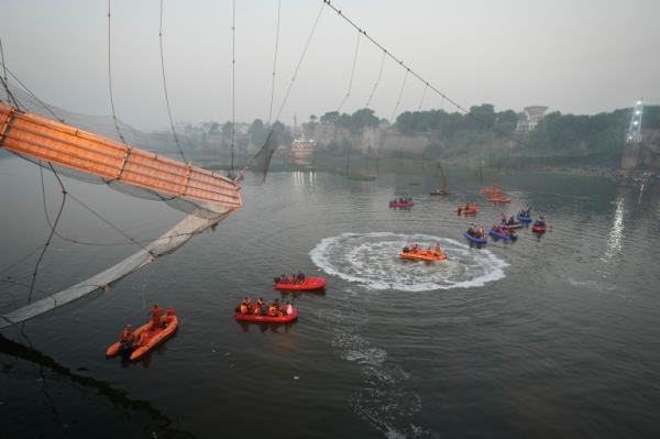 Search and rescue crews in boats carry out operations at the site of a cable suspension bridge collapse in Morbi town of western state Gujarat, India.
