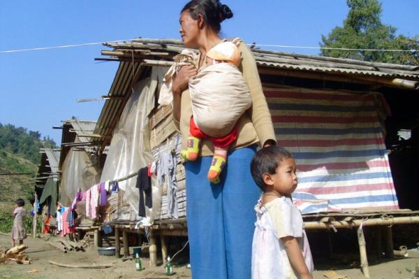 A Kachin refugee woman with children stands outside huts at the Hpun Lum Yang camp for displaced poeple near Laiza in northern Myanmar in 2013 