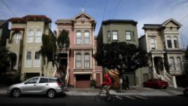 A bicyclist rides by a row of homes on February 18, 2014 in San Francisco, California. According to a report by mortgage resource site HSH.com, an annual salary of $115,510 is needed to purchase a house in San Francisco where the median    home price is $682,410. The report included 25 of the nations largest metropolitan cities with Cleveland, Ohio being the cheapest with a needed salary of $19,435 to purchase a home.  (Photo by Justin Sullivan/Getty Images)