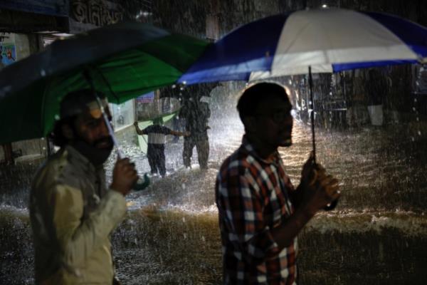 People wade through a flooded street amid continuous rain before the Cyclone Sitrang hits the country in Dhaka, Bangladesh, October 24, 2022