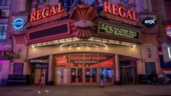 Pedestrians pass in front of a Regal Cinemas movie theater at sunset in New York, U.S., on Tuesday, Oct. 6, 2020. More than 7,000 movie screens will be dark in the U.S. this weekend as the Regal theater chain said it will shut down all 536 locations on Thursday. Photographer: Amir Hamja/Bloomberg via Getty Images