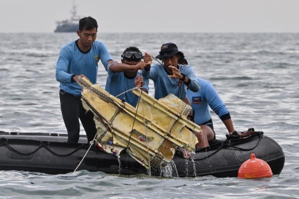 Indonesian Navy divers hold wreckage from Sriwijaya Air flight SJY182 during a search and rescue operation at sea near Lancang island on January 10, 2021, after the Boeing 737-500 crashed shortly after taking off from Jakarta airport on January 9. (Photo by ADEK BERRY / AFP)
