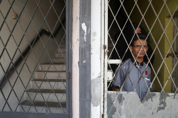 Rohingya refugee and activist Zafar Ahmad Abdul Ghani and his wife look out from behind a metal grille at their home in Kuala Lumpur, Malaysia.