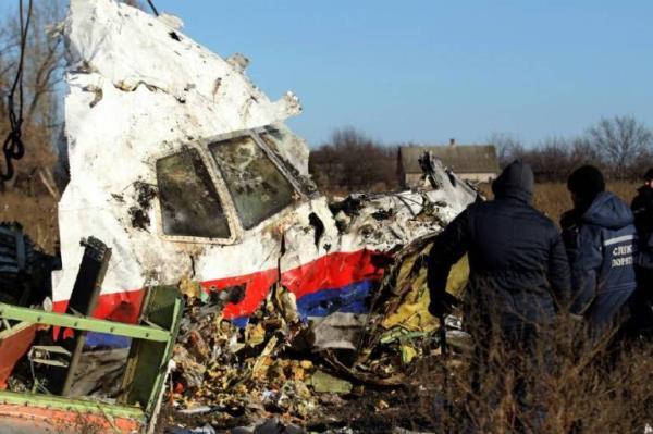 Two workers coming up to front of plane wreck (white with red and blue stripe at bottom) surrounded by debris