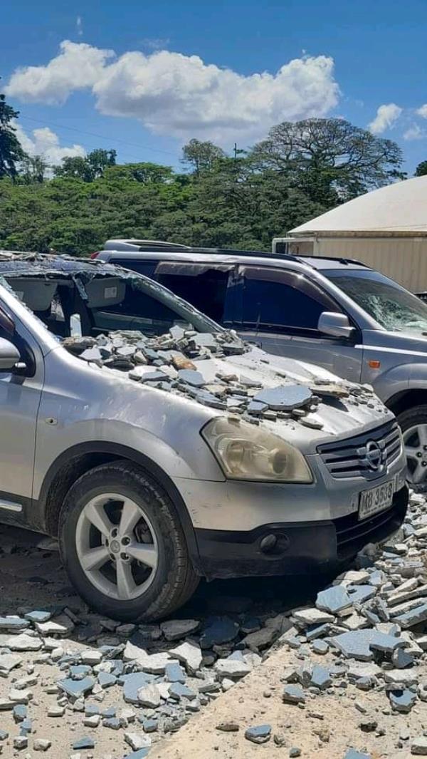 fallen masonry on the crumpled bonnet of parked car with its windscreen smashed