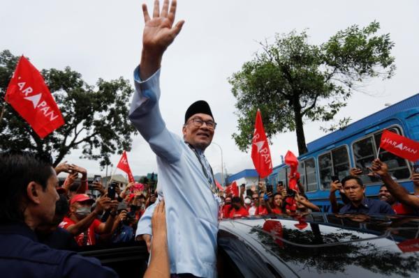 Anwar waves from a car to supporters