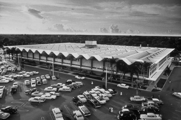Cars fill a parking lot outside a Sears store, circa 1958.