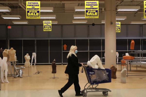 Patti Naleck pushes a cart filled with a mannequin through the Sears store in Woodfield Mall on Nov. 11, 2021, before it permanently closes in Schaumburg, Illinois. Naleck plans to use the mannequin for Halloween displays. 