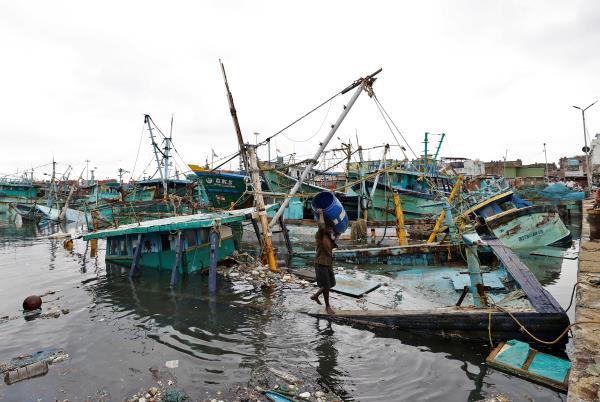 A man carries a plastic drum that he salvaged from his damaged fishing boat following Cyclone Mandous in Chennai
