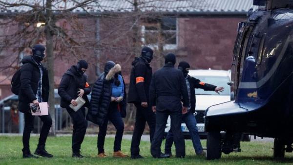 Police escorts a person to a helicopter during Wednesday's raids