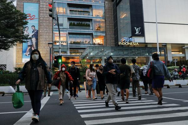 People cross a main road outside a shopping mall during afternoon rush hours in Jakarta