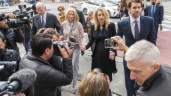 Theranos founder and CEO Elizabeth Holmes, center, walks into federal court with her partner Billy Evans, right, and her parents in San Jose, Calif., Friday, Nov. 18, 2022.  A federal judge will decide whether Holmes should serve a lengthy prison sentence for duping investors and endangering patients while peddling a bogus blood-testing technology. 