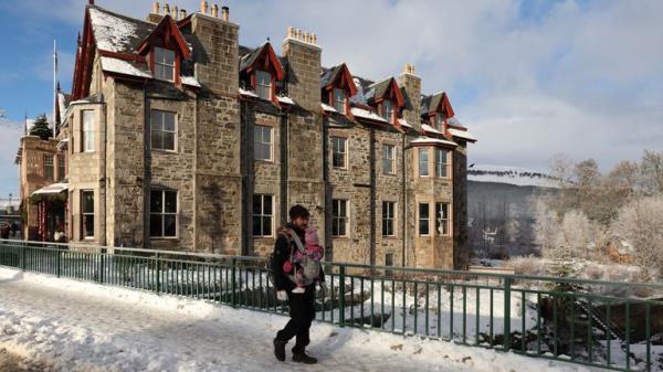 A man walks with a baby in Braemar, Scotland 