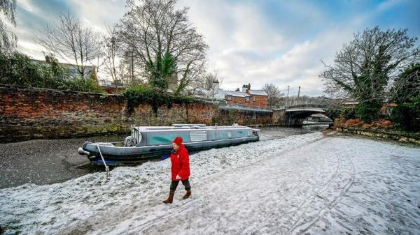 A lady walks past a frozen Bridgewater canal in Lymm, Cheshire. Snow and ice have swept across parts of the UK, with cold wintry conditions set to continue for days 