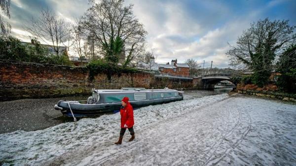 A lady walks past a frozen Bridgewater canal in Lymm, Cheshire. Snow and ice have swept across parts of the UK, with cold wintry conditions set to continue for days. Picture date: Friday December 16, 2022.