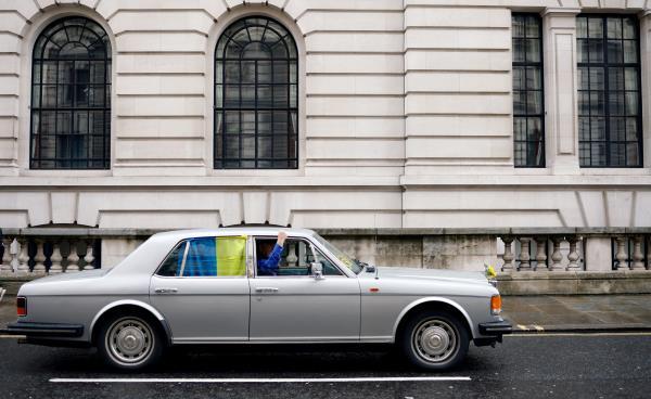The driver of a Rolls Royce, decorated in support of Ukraine, gestures as he drives in Westminster, London