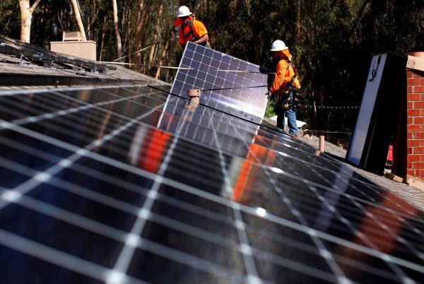 Solar installers from Baker Electric place solar panels on the roof of a residential home in Scripps Ranch, San Diego, California